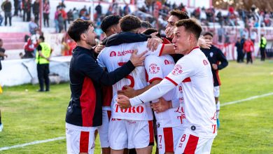 Jogadores de futebol comemoram juntos durante uma partida ao ar livre.