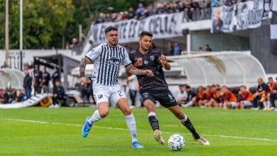 Dois jogadores disputam a bola durante uma partida de futebol em campo aberto.