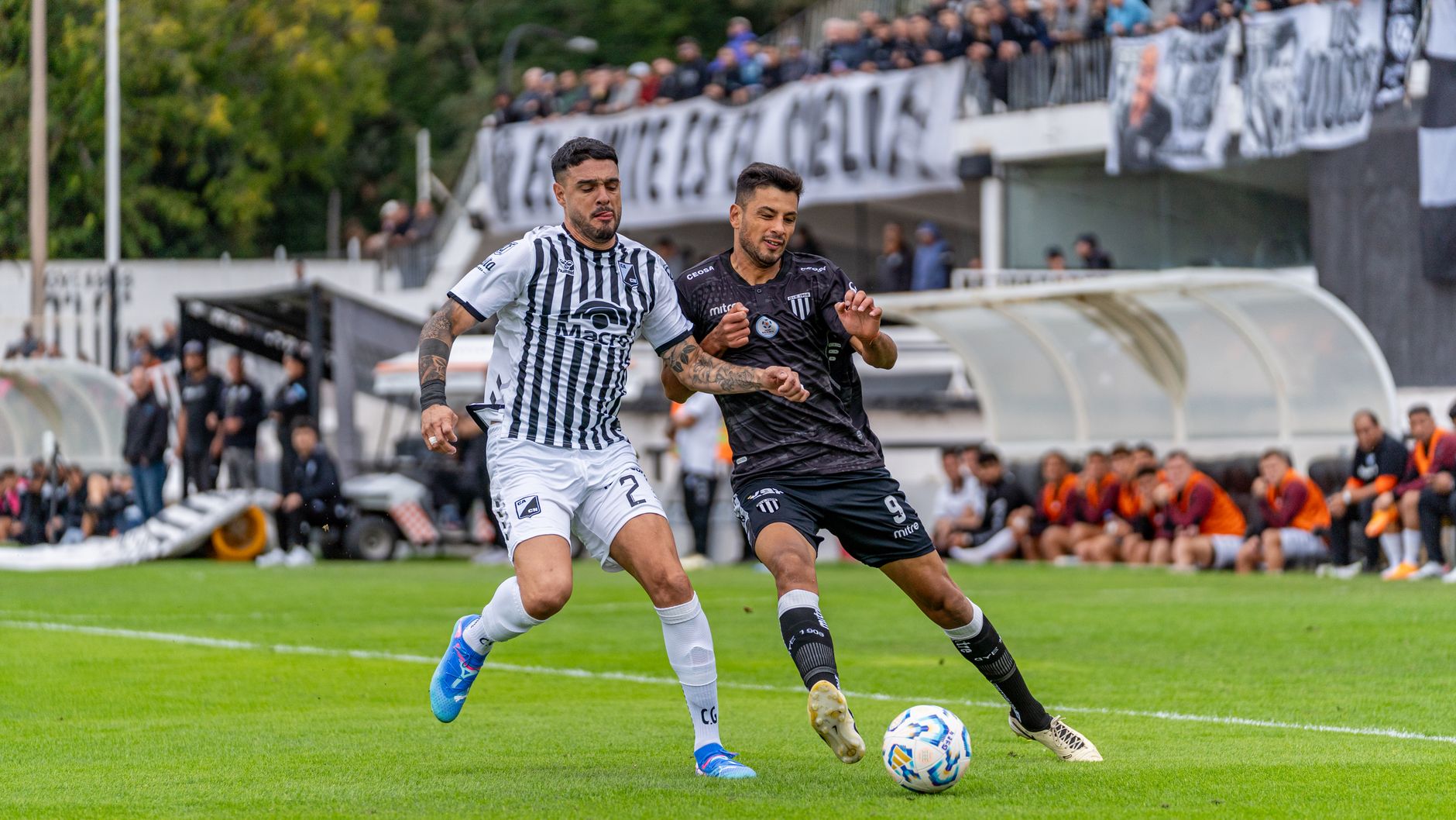 Dois jogadores disputam a bola durante uma partida de futebol em campo aberto.