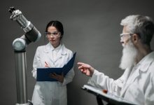 Cientistas de jaleco analisam um equipamento robótico em um laboratório de pesquisa.