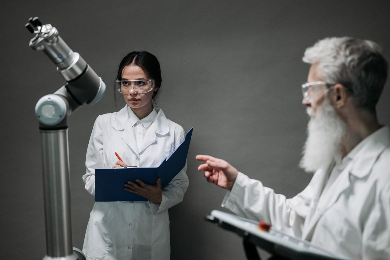 Cientistas de jaleco analisam um equipamento robótico em um laboratório de pesquisa.