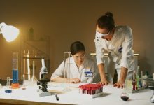 Dois cientistas trabalham juntos em um laboratório, analisando equipamentos e amostras durante um experimento.